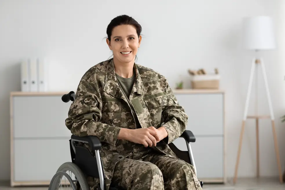 Woman in army uniform in wheelchair smiling confidently at the camera
