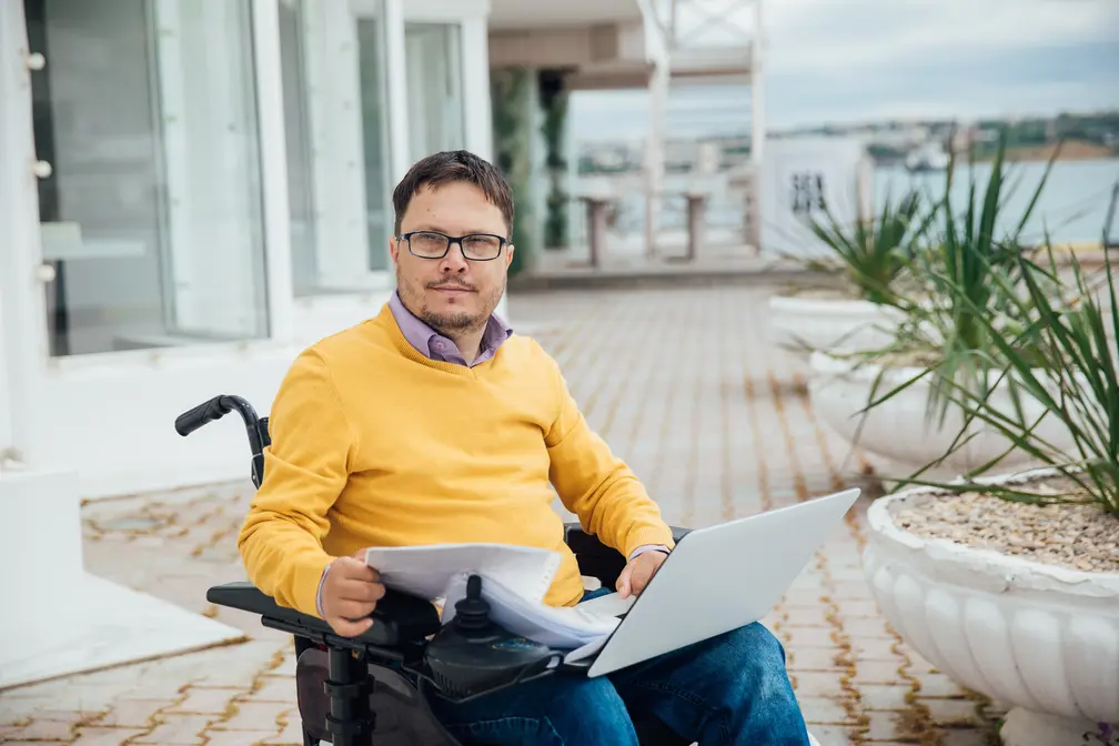 Male participant in wheelchair using laptop to contact Ryre Care
